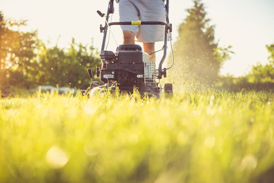 Close-up of a person mowing a sunlit lawn with a gas mower